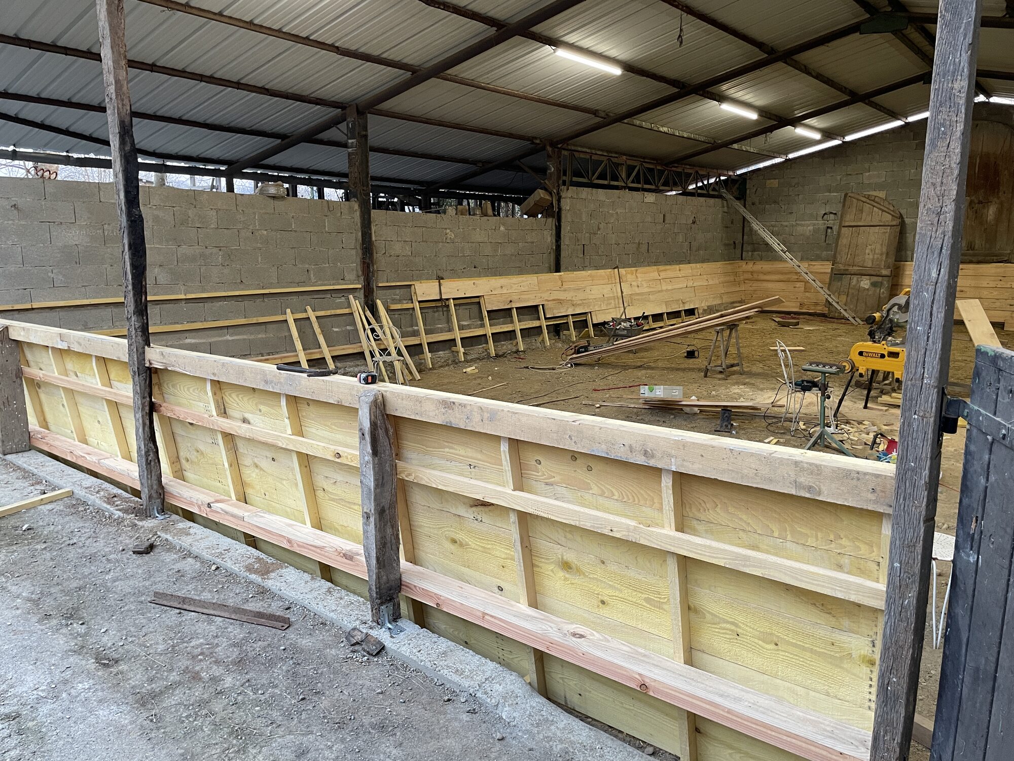 Timber kickboard wall built around an indoor riding arena by B3KM EcoDesign